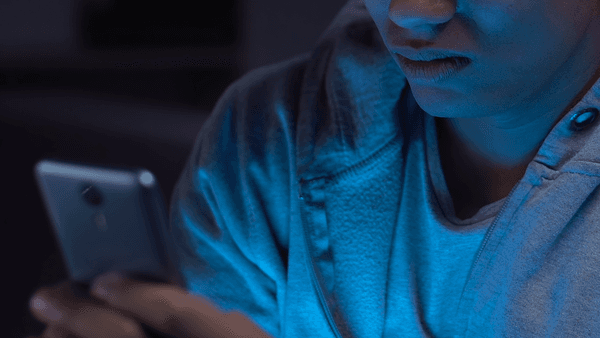 Young man scrolling on mobile phone in the dark